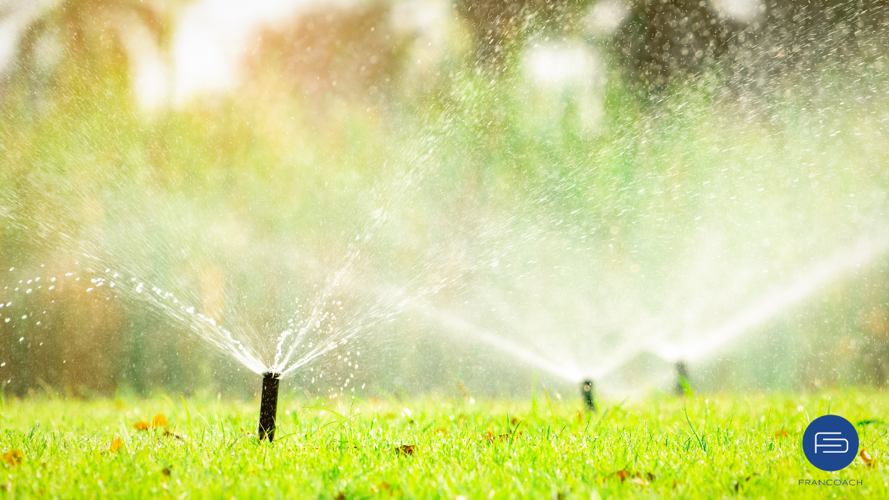 sprinklers running in a green yard, francoach logo is in the corner due to new franchise owner for conserva irrigation